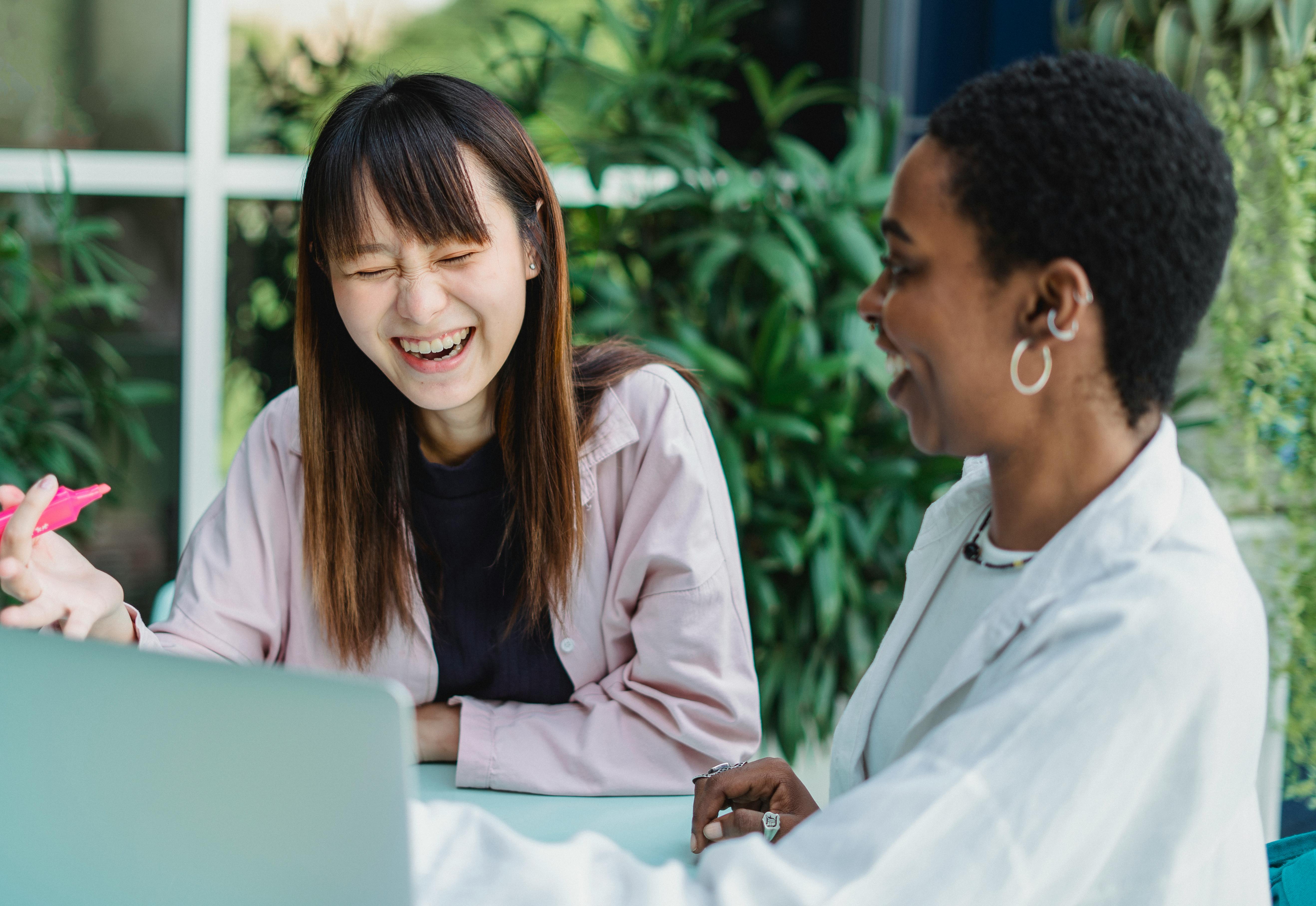 Two women laughing together at a career coaching session
